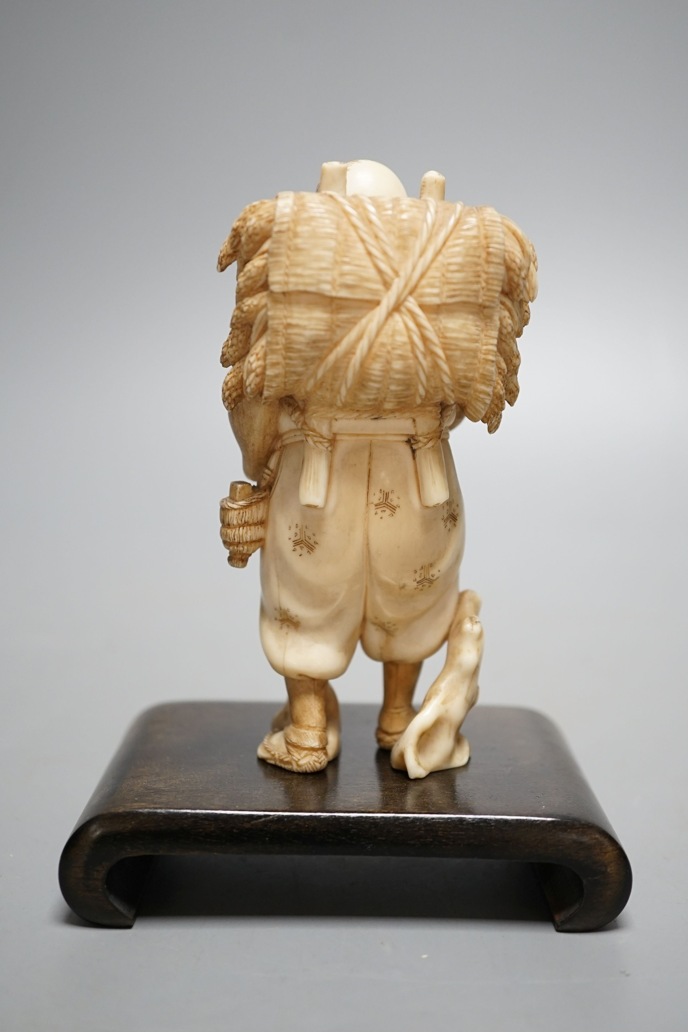 A Japanese ivory figure of a farmer smoking a pipe, Meiji period, signed - 12cm tall